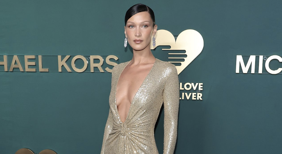 BELLA HADID GLIMMERS IN GOLD PLUNGING DRESS AT GOLDEN HEART AWARDS